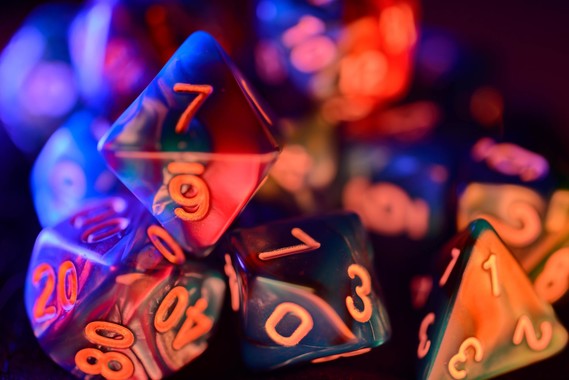 A pile of RPG dice in multicolored lighting.