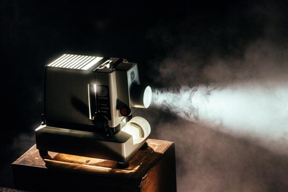 A projector sends a beam of light through fog onto an unseen movie screen.