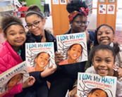 Smiling students holding copies of I Love My Hair