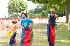 3 young people in a sack race all wearing face masks