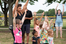 Group of 1 adult and children raising arms