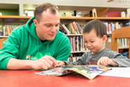 Man reading with young boy at a table