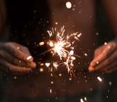 hands and torso of person holding sparklers in the dark