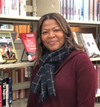 Yolande Wilburn standing in front of library shelves with books cropped from the midsection