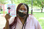 photo of librarian smiling behind mask holding up a book