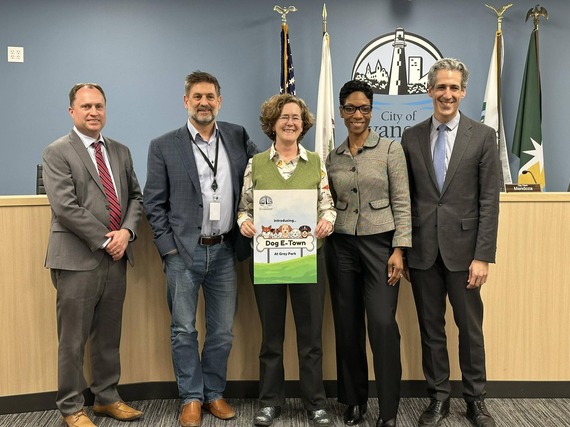 City staff and leadership posing with a dog park sign announcing the winner of the naming contest "Dog E-Town"