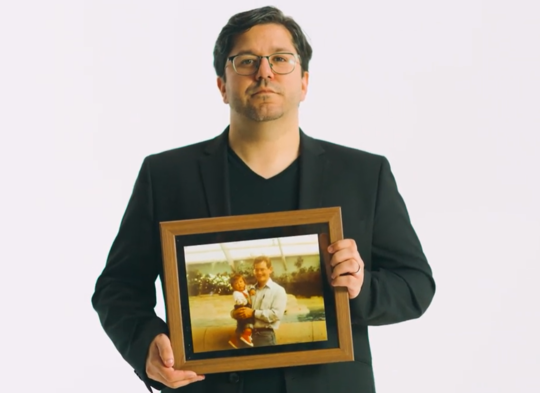 Man holding a photo of another man and baby