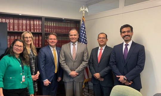 Photo of six people, left to right, women in green shirt, women in black dress, four men in business suits