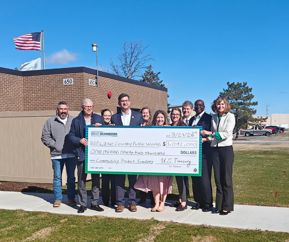 US Representative Brad Schneider, Lake County Board Members and County staff pose with big check received to recognize federal funding. 