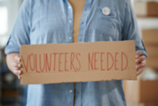 Volunteers needed cardboard sign stock photo
