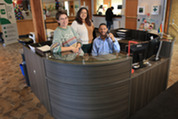 Ele, Paola and Carlton at the Welcome Center desk in the Village Hall lobby