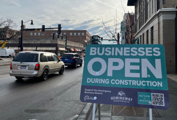 Sign reminding drivers and pedestrians that Hemingway District businesses are open during Renew the Avenue construction.