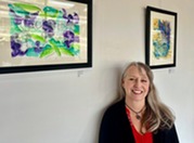 Public Works Management Analyst Linda DeViller in front of her art work at Village Hall