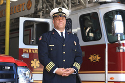 Fire Chief JT Terry stands in uniform in front of a fire engine at the fire house