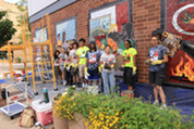 Participants in the 2026 Off the Wall program pose in front of their work as it is installed near North Avenue