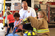 Fire Chief JT Terry helps kids try on fire gear during the 2025 Fire Department open house