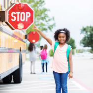 girl pointing to bus stop arm