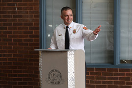 A man, Peoria Fire Chief Shawn Sollberger, gives a speech behind a decorative podium.