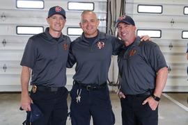 Three Peoria firefighters pose together in the garage at Peoria Fire Central.
