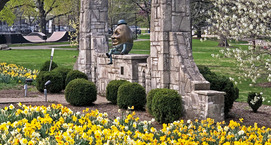 Humpty dumpty sitting on a wall surrounded by daffodils.