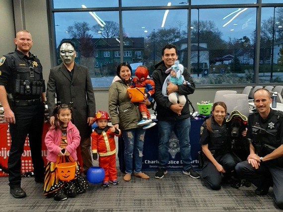 Police officers posing with costumed kids on Halloween.