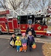 Firefighters pose with trick or treaters in front of a firetruck