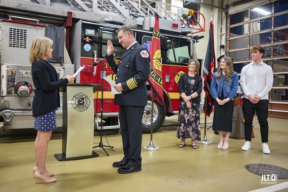 New fire chief is sworn in at fire station one. fire truck in the background.