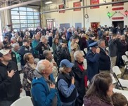 A crowd salutes and puts their hands over their hearts for the National Anthem.