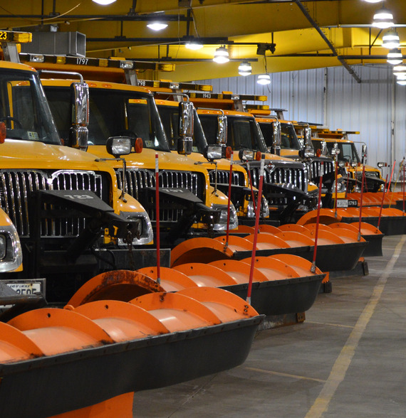 several snowplows lined up in a warehouse.