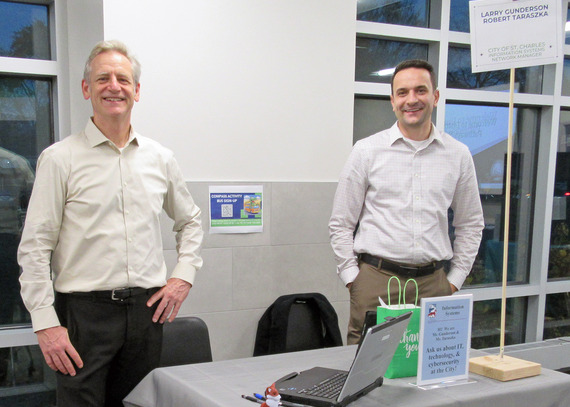 Two men from the IS department standing behind a booth.