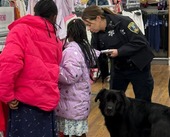 A female cop and k-9 unit shop for items at the Meijer store alongside two kids in need.