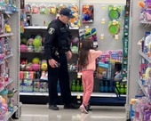 A cop with a child in need shops for items in a store aisle.