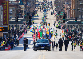 A car with flags leads the parade procession down Main Street in downtown St. Charles.