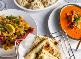 Indian and Nepalese cuisine plated on a table with a white tablecloth.