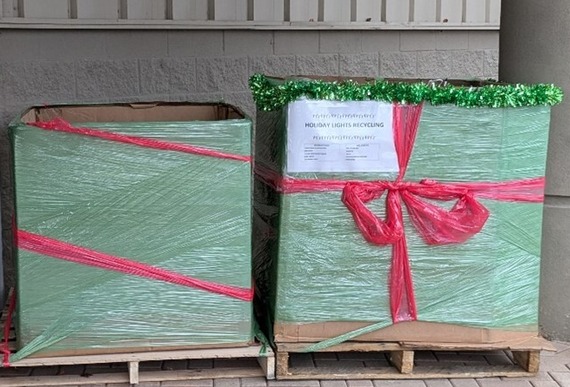 Two large bins wrapped to look like Christmas presents in front of an office building.