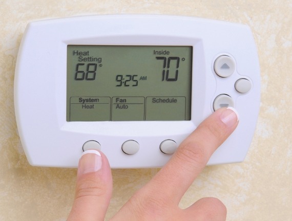 A hand adjusting a thermostat.