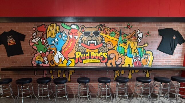 Mural on a brick wall with a bar and stools.