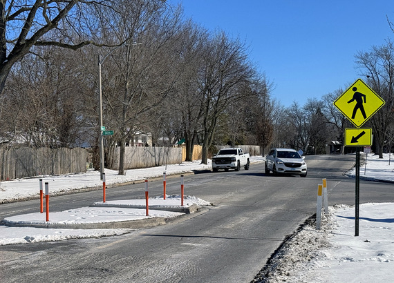 Two cars driving on Prairie Street near a new pedestrian refuge island.