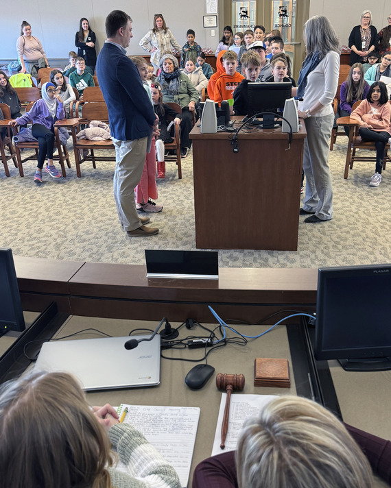Students line up in the council chambers to ask questions during a mock council meeting.