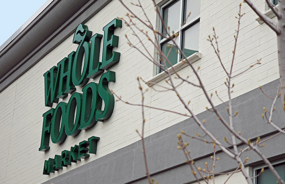 Whole Foods sign on the side of the building with a tree in the foreground.