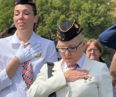 Two women with eyes closed pay tribute to fallen heroes during Memorial Day Ceremony.