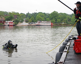 A diver nearly submerged speaks with a firefighter on Boy Scout Island.