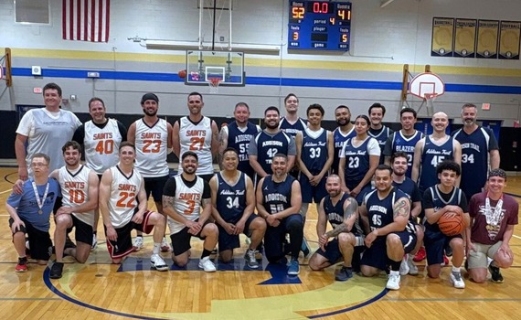 A group shot of two basketball teams during a charity game at a middle school.