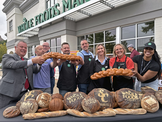 The Mayor, City Council members and staff gather to mark the Whole Foods opening outside with the grocery store in the background.