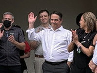 A crowd gathers in front of the new Whole Foods with many attendees to the grand opening clapping.