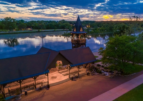 A drone shot of the Pottawatomie Park pavilion with a reflective Fox River and setting sun in the background.