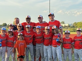 A group shot of baseball players and the mayor standing on the home plate of a field.