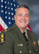 The new police chief in uniform in front of an American flag.