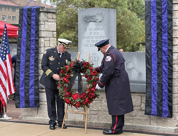 A wreath of flowers stands in front of a memorial to firefighters.