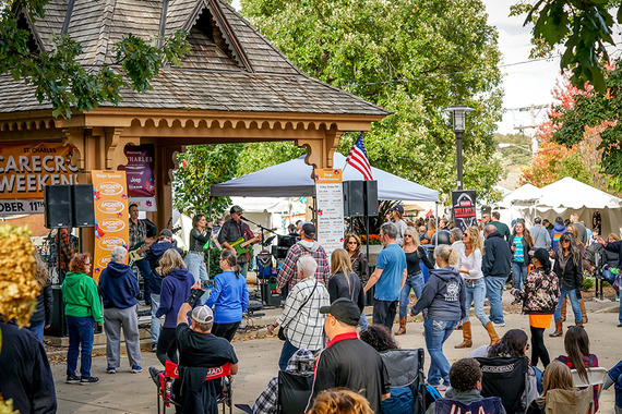 A large crowd gathers at a gazebo while listening to live music in the fall.